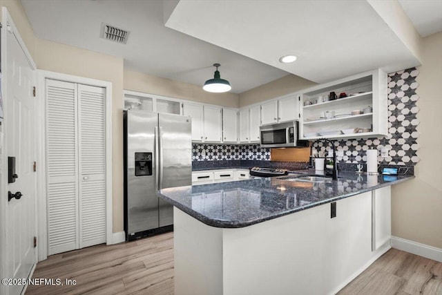 2168 Minorcan St, Middleburg, FL 32068 - kitchen with appliances with stainless steel finishes, open shelves, light wood-style floors, a peninsula, and dark stone counters