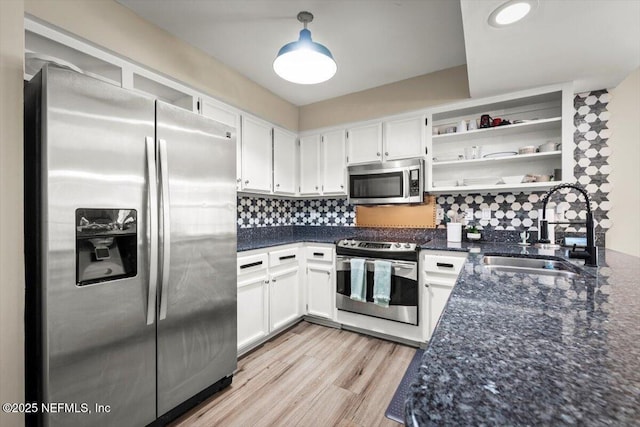2168 Minorcan St, Middleburg, FL 32068 - kitchen featuring appliances with stainless steel finishes, open shelves, dark stone countertops, white cabinets, and light wood-style floors