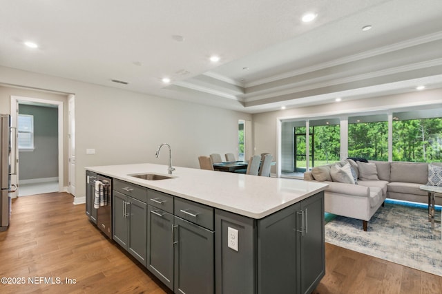 613 Witty Banter Ct, Yulee, FL 32097 - kitchen with crown molding, wine cooler, a kitchen island with sink, gray cabinetry, and a raised ceiling