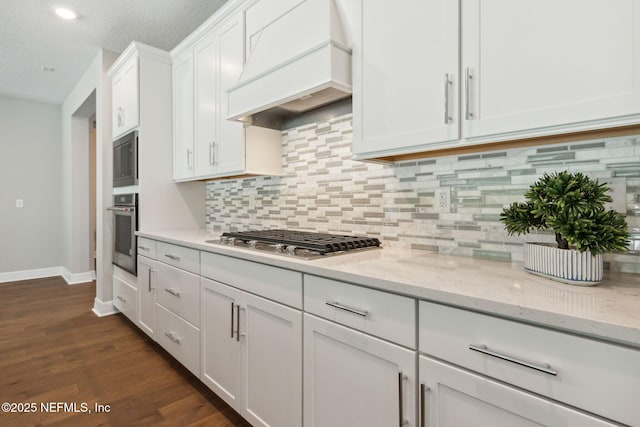 613 Witty Banter Ct, Yulee, FL 32097 - kitchen featuring appliances with stainless steel finishes, custom range hood, white cabinetry, tasteful backsplash, and light stone countertops