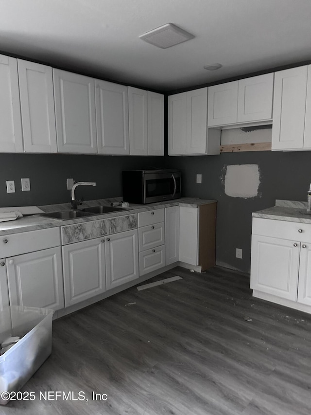 9846 Highland Ave, Jacksonville, FL 32208 - kitchen with stainless steel microwave, dark wood finished floors, white cabinetry, and light countertops