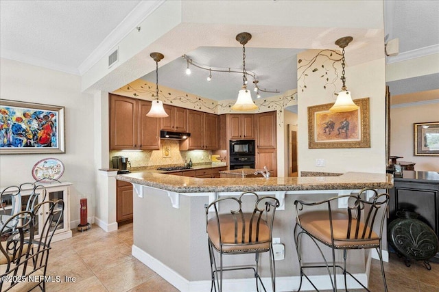 201 S Ocean Grande Dr Unit 104, Ponte Vedra Beach, FL 32082 - kitchen featuring under cabinet range hood, a kitchen bar, black appliances, ornamental molding, and brown cabinets