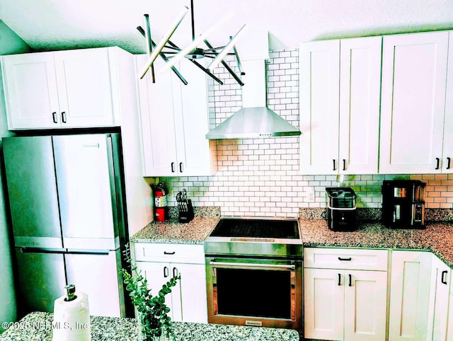 25 Fullerwood Dr, Saint Augustine, FL 32084 - kitchen with freestanding refrigerator, stove, tasteful backsplash, white cabinets, and wall chimney range hood