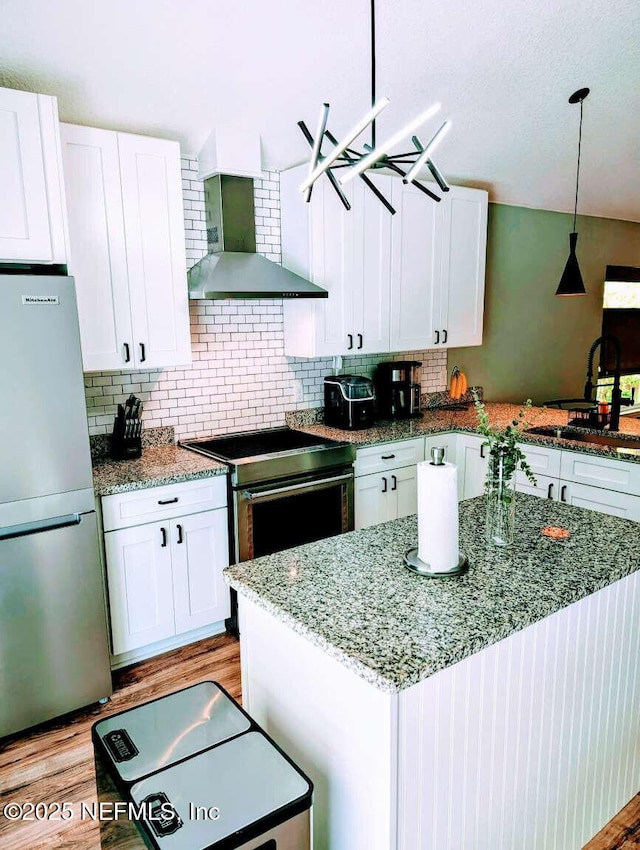 25 Fullerwood Dr, Saint Augustine, FL 32084 - kitchen featuring appliances with stainless steel finishes, wall chimney exhaust hood, white cabinetry, and light wood-style floors