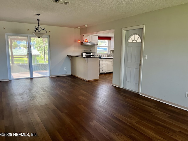 118 Magnolia Dr, East Palatka, FL 32131 - kitchen with a peninsula, dark countertops, dark wood-style flooring, white cabinetry, and a textured ceiling