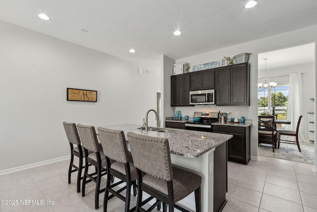 86180 Tranquil Ct, Yulee, FL 32097 - kitchen featuring stainless steel appliances, a kitchen breakfast bar, a center island with sink, a chandelier, and light stone countertops