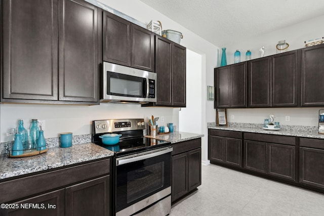 86180 Tranquil Ct, Yulee, FL 32097 - kitchen featuring stainless steel appliances, dark brown cabinets, light stone countertops, and light tile patterned floors