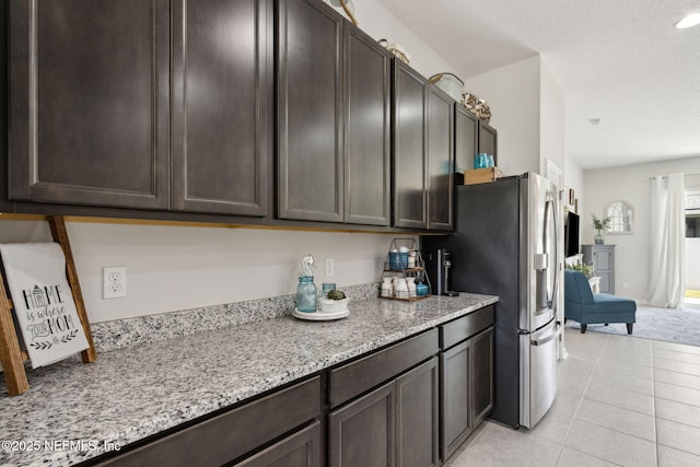 86180 Tranquil Ct, Yulee, FL 32097 - kitchen featuring stainless steel refrigerator with ice dispenser, dark brown cabinets, light stone countertops, and light tile patterned floors