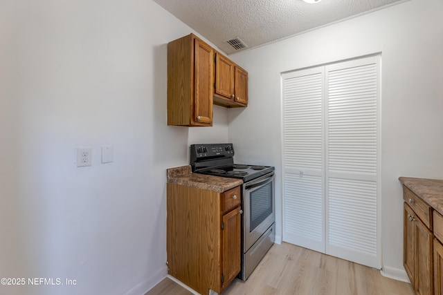 3122 20th St, Jacksonville, FL 32254 - kitchen featuring stainless steel electric range, brown cabinets, light wood-type flooring, a textured ceiling, and dark countertops
