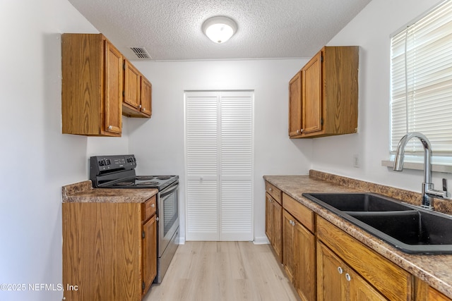 3122 20th St, Jacksonville, FL 32254 - kitchen featuring electric range, light wood-style flooring, brown cabinets, and a textured ceiling