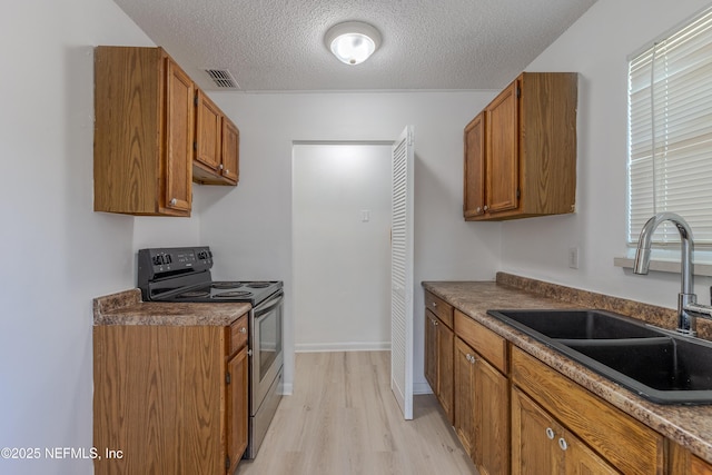 3122 20th St, Jacksonville, FL 32254 - kitchen featuring electric range, brown cabinets, light wood-style flooring, a textured ceiling, and dark countertops