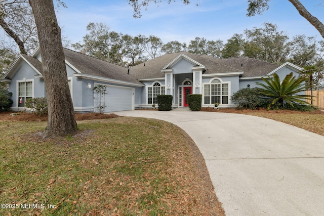 2205 Ashley Ct, Fernandina Beach, FL 32034 - view of front of home with concrete driveway, an attached garage, stucco siding, roof with shingles, and a front yard