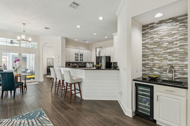 2205 Ashley Ct, Fernandina Beach, FL 32034 - kitchen with wine cooler, stainless steel refrigerator with ice dispenser, dark countertops, tasteful backsplash, and white cabinetry