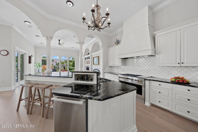 23 Corona Rd, Ponte Vedra Beach, FL 32082 - kitchen featuring stainless steel appliances, a center island with sink, light wood-type flooring, tasteful backsplash, and white cabinets