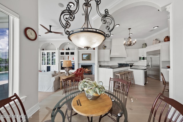 23 Corona Rd, Ponte Vedra Beach, FL 32082 - dining room featuring ornamental molding, ceiling fan, a chandelier, a lit fireplace, and light wood-style floors