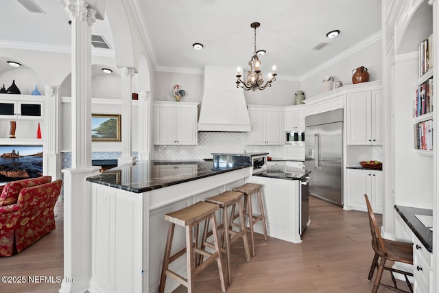 23 Corona Rd, Ponte Vedra Beach, FL 32082 - kitchen with built in refrigerator, premium range hood, white cabinetry, tasteful backsplash, and wood finished floors