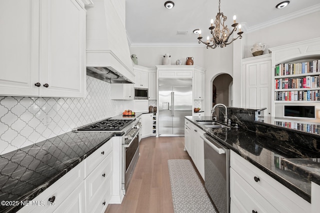23 Corona Rd, Ponte Vedra Beach, FL 32082 - kitchen with built in appliances, arched walkways, premium range hood, a chandelier, and white cabinets