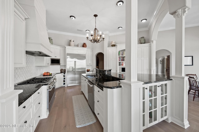 23 Corona Rd, Ponte Vedra Beach, FL 32082 - kitchen with built in appliances, arched walkways, premium range hood, tasteful backsplash, and dark wood-style floors