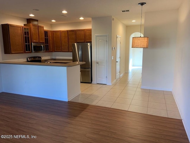 13312 Low Tide Way, Jacksonville, FL 32258 - kitchen with stainless steel appliances, glass insert cabinets, light wood-type flooring, recessed lighting, and a peninsula