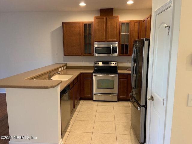 13312 Low Tide Way, Jacksonville, FL 32258 - kitchen featuring appliances with stainless steel finishes, a peninsula, recessed lighting, glass insert cabinets, and brown cabinets