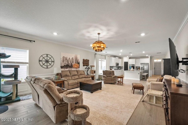 75013 Pondside Ln, Yulee, FL 32097 - living area featuring crown molding, a chandelier, light wood finished floors, recessed lighting, and wainscoting