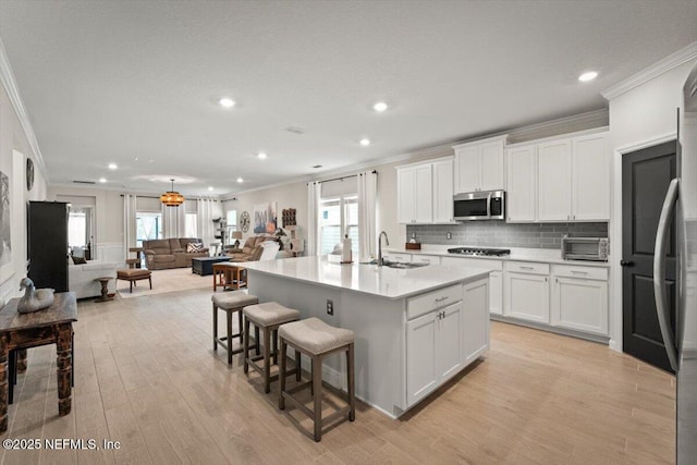 75013 Pondside Ln, Yulee, FL 32097 - kitchen with stainless steel microwave, ornamental molding, open floor plan, light wood-style flooring, and recessed lighting