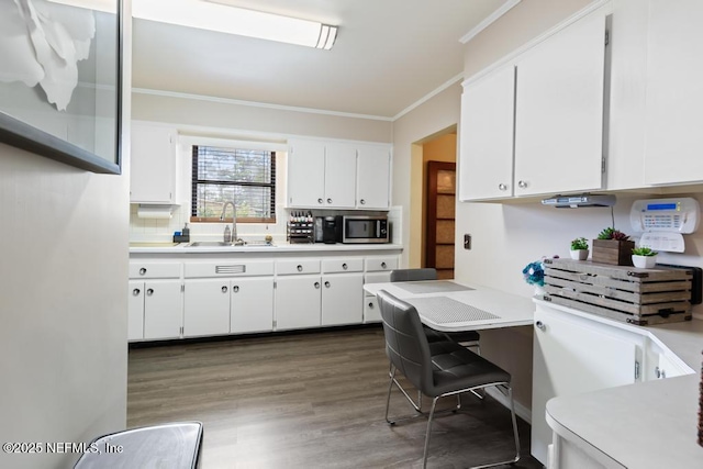 2510 Cesery Blvd, Jacksonville, FL 32211 - kitchen with stainless steel microwave, light countertops, ornamental molding, white cabinetry, and dark wood-style flooring