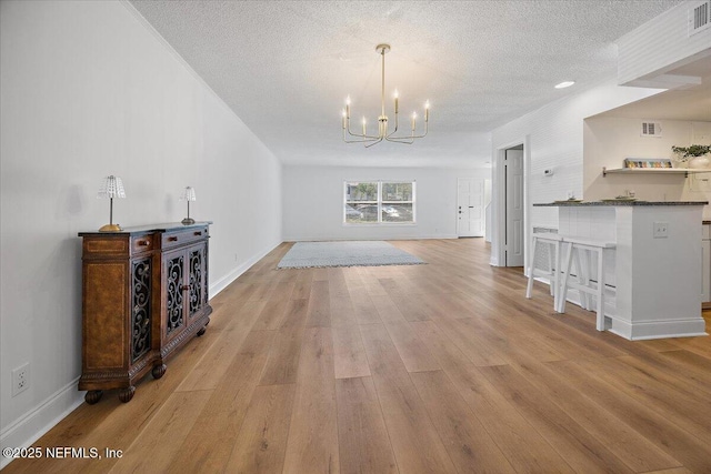 695 A1A Unit 146, Ponte Vedra Beach, FL 32082 - unfurnished living room featuring a chandelier, light wood-type flooring, and a textured ceiling