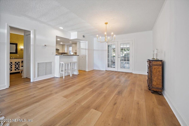 695 A1A Unit 146, Ponte Vedra Beach, FL 32082 - unfurnished living room featuring a chandelier, a textured ceiling, and light wood-style flooring
