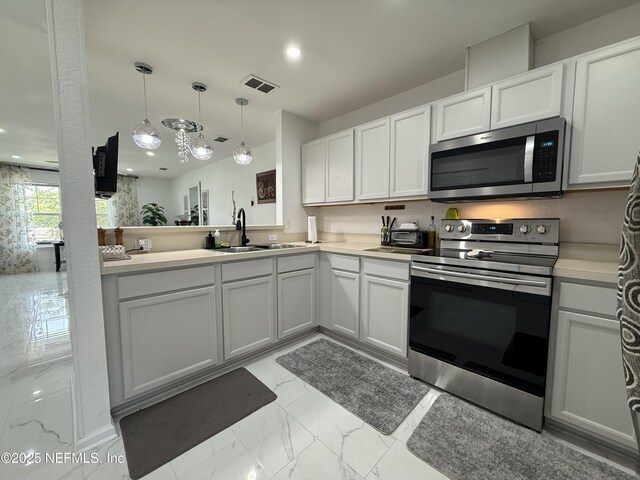 106 Sunrise Ct, Atlantic Beach, FL 32233 - kitchen with appliances with stainless steel finishes, light countertops, light marble finish floors, decorative light fixtures, and white cabinets