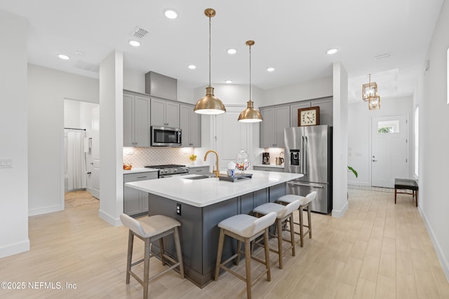985 Rustic Mill Dr, Saint Augustine, FL 32092 - kitchen with appliances with stainless steel finishes, gray cabinets, a breakfast bar area, light wood-type flooring, and recessed lighting