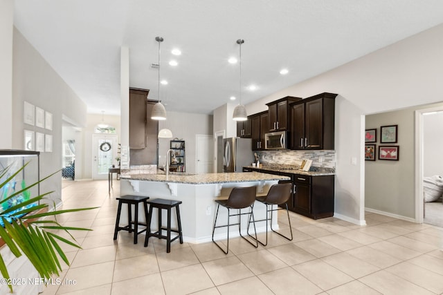 95212 Tanglewood Dr, Fernandina Beach, FL 32034 - kitchen with appliances with stainless steel finishes, dark brown cabinets, light tile patterned flooring, a kitchen breakfast bar, and tasteful backsplash
