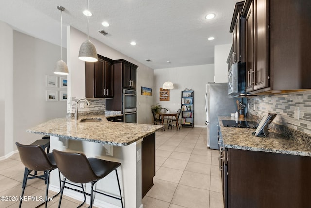 95212 Tanglewood Dr, Fernandina Beach, FL 32034 - kitchen with dark brown cabinets, stainless steel appliances, tasteful backsplash, light stone countertops, and a kitchen bar