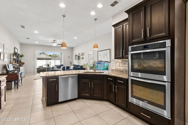 95212 Tanglewood Dr, Fernandina Beach, FL 32034 - kitchen featuring stainless steel appliances, open floor plan, a peninsula, dark brown cabinetry, and light stone counters
