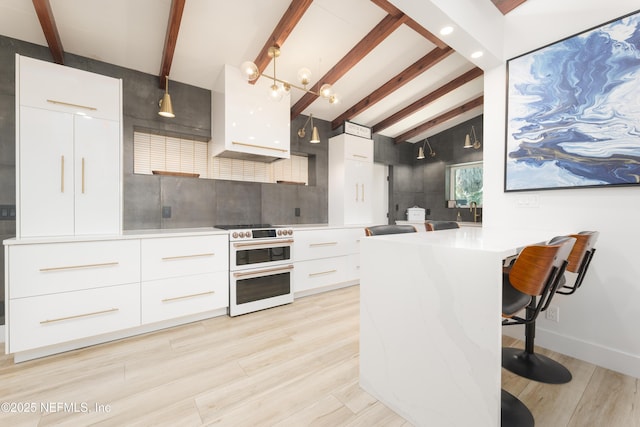 411 S St, Neptune Beach, FL 32266 - kitchen with range with two ovens, modern cabinets, decorative backsplash, white cabinetry, and light countertops
