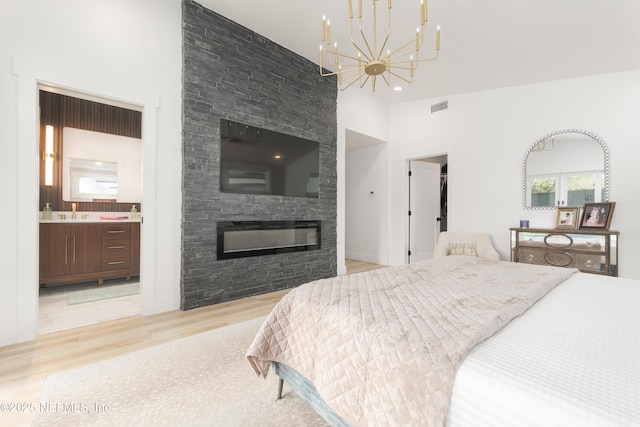411 S St, Neptune Beach, FL 32266 - bedroom featuring light wood-type flooring, a chandelier, a fireplace, ensuite bathroom, and a high ceiling