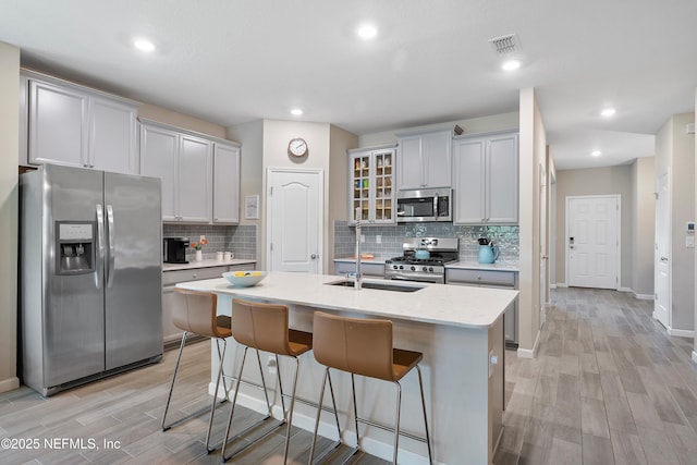 71 Ash Breeze Cv, Saint Augustine, FL 32095 - kitchen with stainless steel appliances, light wood-type flooring, tasteful backsplash, a kitchen breakfast bar, and an island with sink