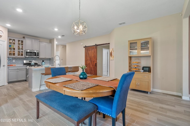71 Ash Breeze Cv, Saint Augustine, FL 32095 - dining area featuring a barn door, light wood-type flooring, a chandelier, and recessed lighting