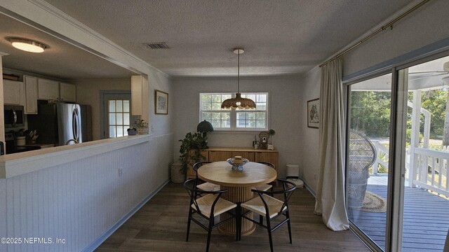 1319 Hickory St, Fernandina Beach, FL 32034 - dining space featuring dark wood finished floors, a textured ceiling, and ornamental molding