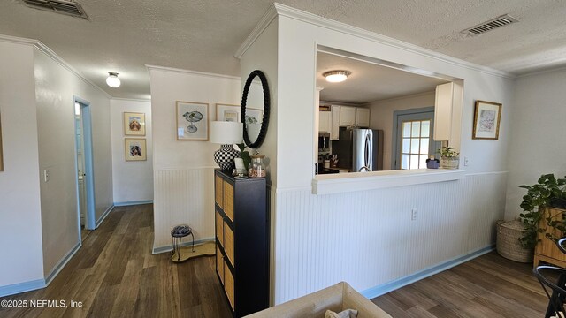 1319 Hickory St, Fernandina Beach, FL 32034 - corridor featuring wood finished floors, a textured ceiling, ornamental molding, and wainscoting