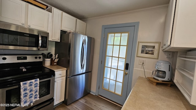 1319 Hickory St, Fernandina Beach, FL 32034 - kitchen featuring appliances with stainless steel finishes, ornamental molding, white cabinetry, light countertops, and light wood-type flooring