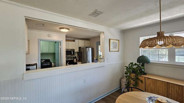 1319 Hickory St, Fernandina Beach, FL 32034 - kitchen with appliances with stainless steel finishes, dark wood finished floors, a textured ceiling, a wainscoted wall, and crown molding