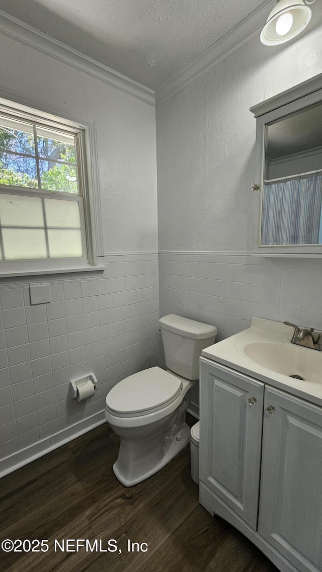 1319 Hickory St, Fernandina Beach, FL 32034 - bathroom featuring tile walls, wood finished floors, crown molding, vanity, and wainscoting
