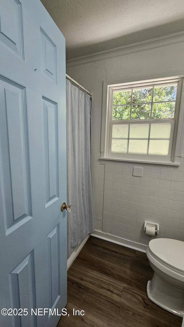 1319 Hickory St, Fernandina Beach, FL 32034 - full bathroom with wood finished floors, a textured ceiling, tile walls, and a shower with curtain