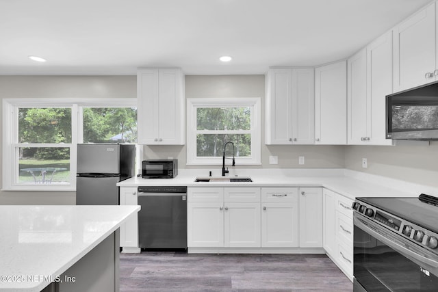 11707 Village Ln, Jacksonville, FL 32223 - kitchen with appliances with stainless steel finishes, recessed lighting, white cabinetry, and light wood-type flooring