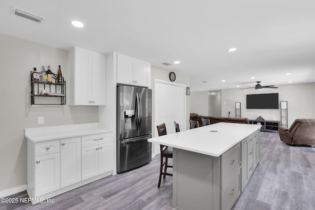 11707 Village Ln, Jacksonville, FL 32223 - kitchen with stainless steel fridge, open floor plan, a ceiling fan, light wood-style flooring, and white cabinets
