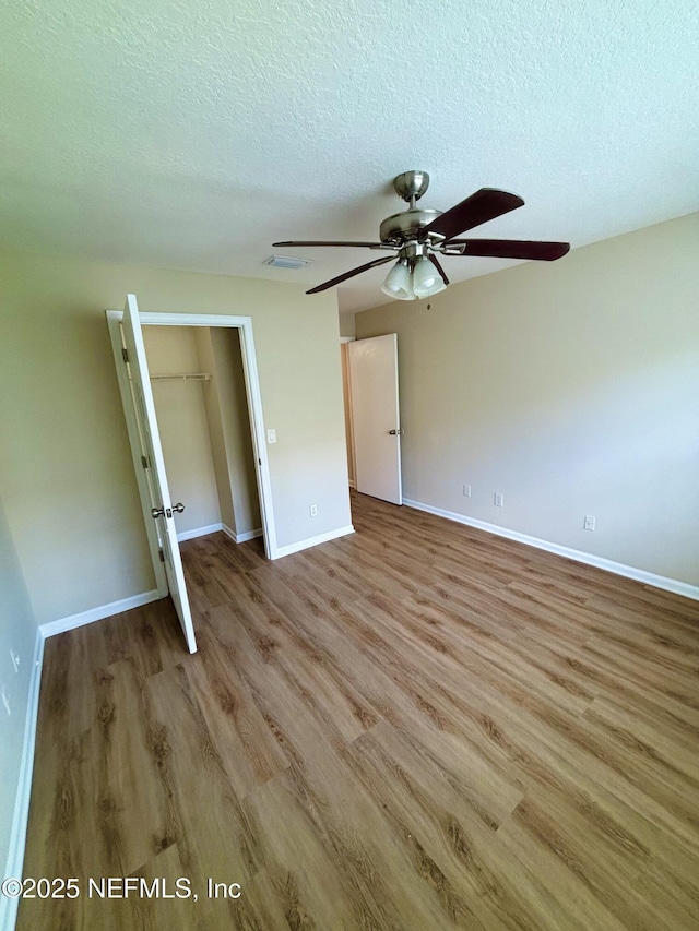 7701 Timberlin Park Blvd Unit 322, Jacksonville, FL 32256 - unfurnished bedroom featuring wood finished floors, a textured ceiling, a closet, a spacious closet, and a ceiling fan
