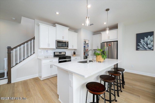 143 Dahlia Falls Dr, Saint Johns, FL 32259 - kitchen featuring stainless steel appliances, light wood-type flooring, tasteful backsplash, a breakfast bar, and white cabinets