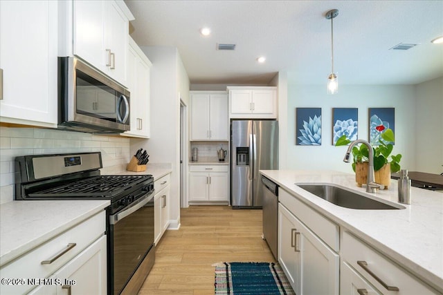 143 Dahlia Falls Dr, Saint Johns, FL 32259 - kitchen featuring stainless steel appliances, light wood-type flooring, white cabinetry, hanging light fixtures, and decorative backsplash