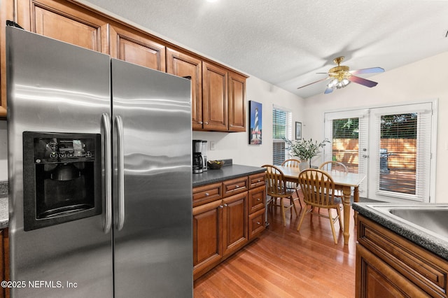 122 Twine St, Saint Augustine, FL 32084 - kitchen featuring stainless steel refrigerator with ice dispenser, dark countertops, light wood finished floors, a ceiling fan, and brown cabinets